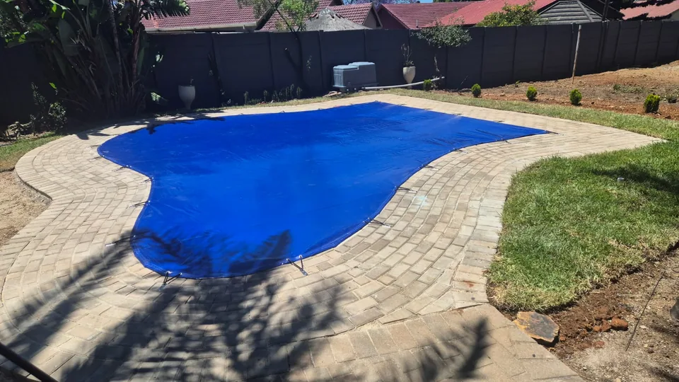 Blue solid cover custom shaped to follow the curved perimeter of a freeform pool