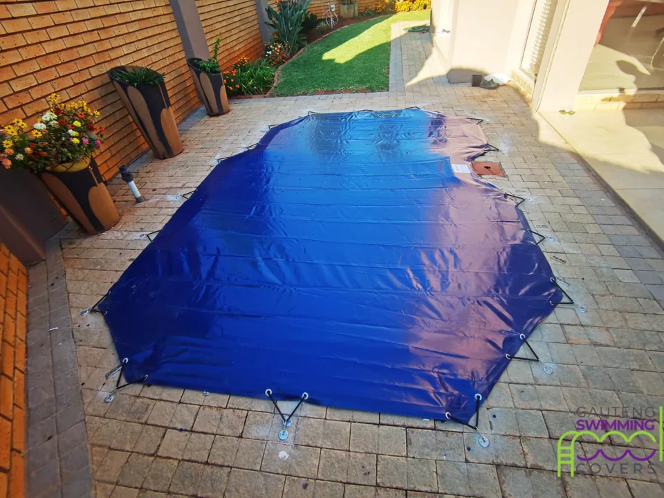 Compact blue cover following the non-rectangular shape of a courtyard pool