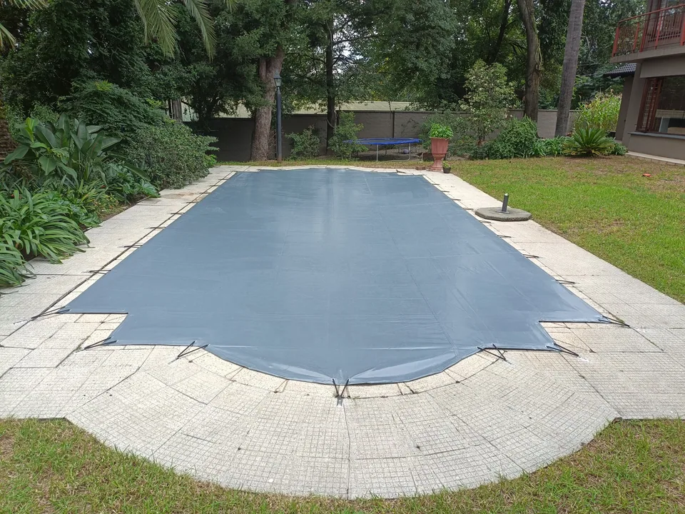 Grey solid cover with shaped cut-outs and a curved end, surrounded by a garden