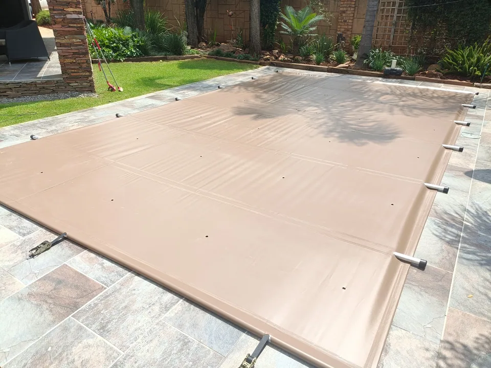 Sand-coloured solid cover with visible aluminium support poles and ratchet straps